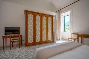 a bedroom with a bed and a desk and a window at Pensione Di Lustro in Forio d'Ischia