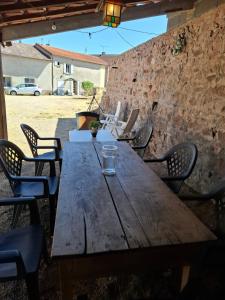 a wooden table with chairs and a glass on it at La colline de Tara in Andelaroche