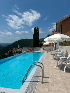a large swimming pool with chairs and umbrellas at Hotel Panorama in Cerreto di Spoleto