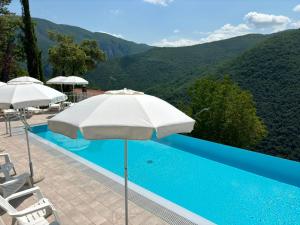 a swimming pool with an umbrella and chairs and mountains at Hotel Panorama in Cerreto di Spoleto