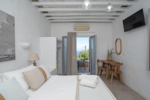 a white bedroom with a bed and a table at Windmill Bella Vista in Artemonas +224 photos
