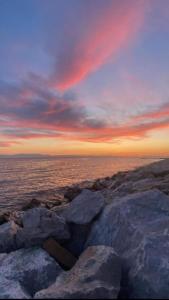 a sunset over the ocean with rocks in the foreground at Epanomi Family Apartments in Epanomi