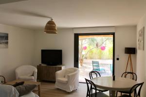 a living room with a tv and a table and chairs at RDC dans maison "ilolil" a 1km plage de la Coudoulière in Six-Fours-les-Plages