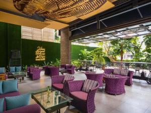 a patio with purple chairs and tables in a restaurant at Mercure Surabaya Grand Mirama in Surabaya