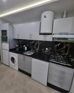 a kitchen with white cabinets and a sink and a stove at Comforts apartment 3 in Fnidek