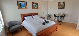 a bedroom with a bed and a chair and a table at Cosy Haven - Large Comfy Dwelling in Mandurah +19 photos