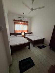 a room with two beds and a window at Kamaleswari Villa Trincomalee in Trincomalee