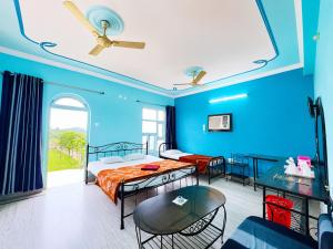 a blue room with two beds and a table at The Binapani Hotel And Restaurant in Tarapith