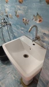 a sink in a bathroom with fish on the wall at Mi HOMESTAY in Bikaner