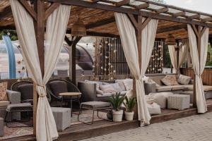 eine Pergola mit Stühlen und Sofas auf einer Terrasse in der Unterkunft BOHO HOUSE in Ustrzyki Dolne