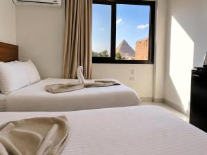 a hotel room with two beds and a window at Prince Pyramid HoteLL in Cairo