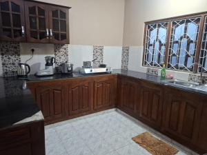 a kitchen with wooden cabinets and a window at Kamaleswari Villa Trincomalee in Trincomalee