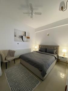 a white bedroom with a bed and a chair and lamps at Apartament Debres Concept in Aiud