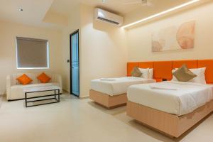 a bedroom with two beds and a couch at Casa Hotel Hitech City in Hyderabad