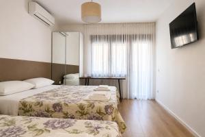 a hotel room with two beds and a television at Apartments Mara near Split Airport in Kastel Stafilic