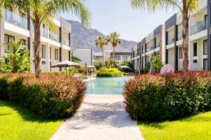 a courtyard with a pool and palm trees and buildings at Palmera Resort Wellness & Spa - Mountain & Pool View Studio 1 by Azur Prime in Vasilia