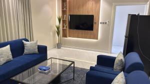 a living room with blue couches and a tv at شقق نطوان المفروشة in Abha