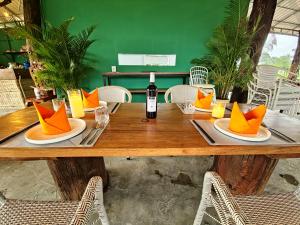 a wooden table with a bottle of wine and orange napkins at Cow Barn Cafe and Lodge Preah Vihear in Phumĭ Nhông +39 photos