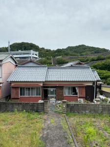 a red house with a fence in front of it at ゲストハウス奥白浜 in Shirahama