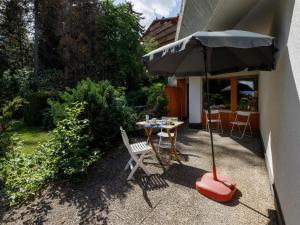 a patio with an umbrella and a table and chairs at Studio Terrasse Des Alpes 618 by Interhome in Crans-Montana