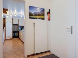 a kitchen with white cabinets and a tv on the wall at Apartment Chalet Almis 5 by Interhome in Grindelwald