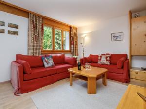 a living room with two red couches and a table at Apartment Terrasse Des Alpes 917 by Interhome in Crans-Montana