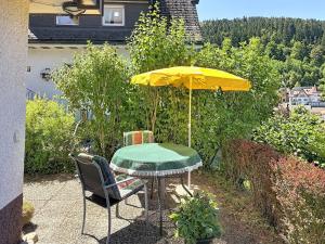 a table with a yellow umbrella and two chairs at Apartment Maier-1 by Interhome in Triberg