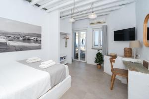 a white bedroom with a bed and a desk at Windmill Bella Vista in Artemonas