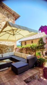 a patio with a couch and an umbrella at Castellare in Chiusdino