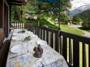 a table with plates and wine glasses on a balcony at Apartment Chalet L'Aube by Interhome in Vers L'Eglise
