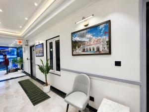 a white room with a chair and a painting on the wall at NEAR SHREE RAM JANM BHOOMI - HOTEL SHREE RR - Wi-Fi - Parking- Luxury Rooms - Best Family Hotel In Ayodhya in Ayodhya
