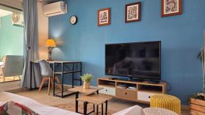 a living room with a large flat screen tv on a blue wall at L'Arymarius 12 in Saint-Pierre
