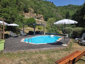 a swimming pool with an umbrella and a table and a bench at le rivalet in Montaigut-le-Blanc