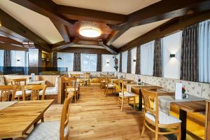 a restaurant with wooden tables and chairs and windows at Luxus Suite mit Whirlpool im Hotel Rupertihof in Ainring