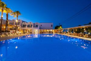 a large swimming pool at night with palm trees at Kamari Beach Hotel in Kamari +42 photos