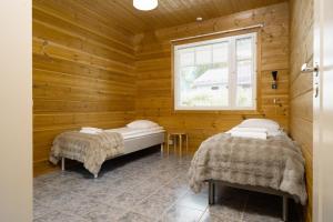 two beds in a wooden room with a window at Apartment A 3 Talja, Private Sauna By Lapland Host in Rovaniemi