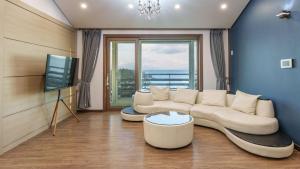 a living room with a white couch and a tv at Yangyang Haetteuneun Changmun Pet-Friend in Yangyang
