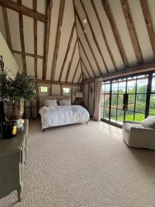 a bedroom with a bed in a room with windows at Surrey Barn, Newly Renovated in Ripley