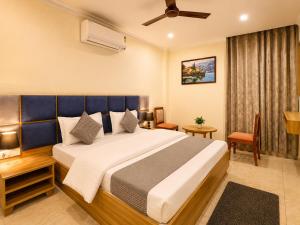 a bedroom with a large bed with a blue headboard at Hotel Andies in Mohali +157 photos