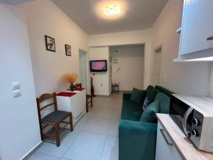 a living room with a green couch and a tv at IRIS Apartment in Loutraki