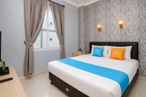 a bedroom with a bed with orange and blue pillows at Sans Vibes Flamenco Hotel in Jakarta