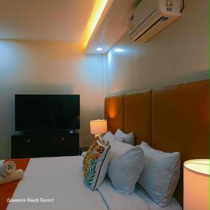 a hotel room with a bed with pillows and a television at Oceanaire Beach Resort ELYU in Bacnotan