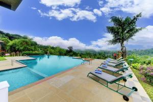 a group of lounge chairs sitting next to a swimming pool at Indo Asia Heritage Coorg, formerly Heritage Resort Coorg in Madikeri
