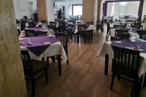 a dining room with tables and chairs with purple tablecloths at Hotel Venus in Slănic-Moldova