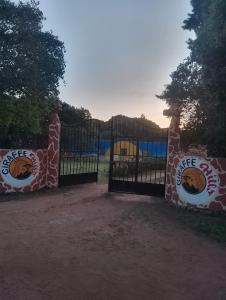 a gate at a zoo with giraffes painted on it at Giraffe Hills Mara Camp in Ololaimutiek +10 photos