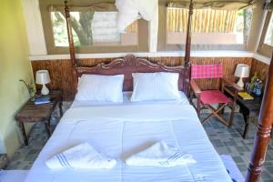a bedroom with a bed with white sheets and two tables at Giraffe Hills Mara Camp in Ololaimutiek