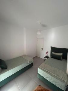 a bedroom with two beds and a white wall at IRIS Apartment in Loutraki