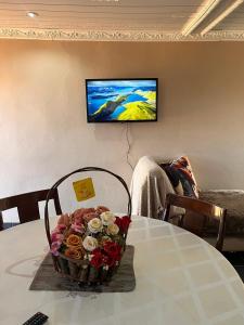 a basket of flowers on a table with a tv on the wall at Nairobi Guesthouse in Orkney