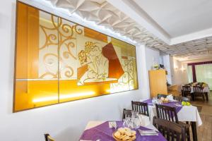 a dining room with a large painting on the wall at Hotel Venus in Slănic-Moldova