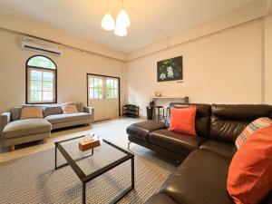 a living room with a leather couch and a table at Neveu Premier Residence : Ratchada in Bangkok